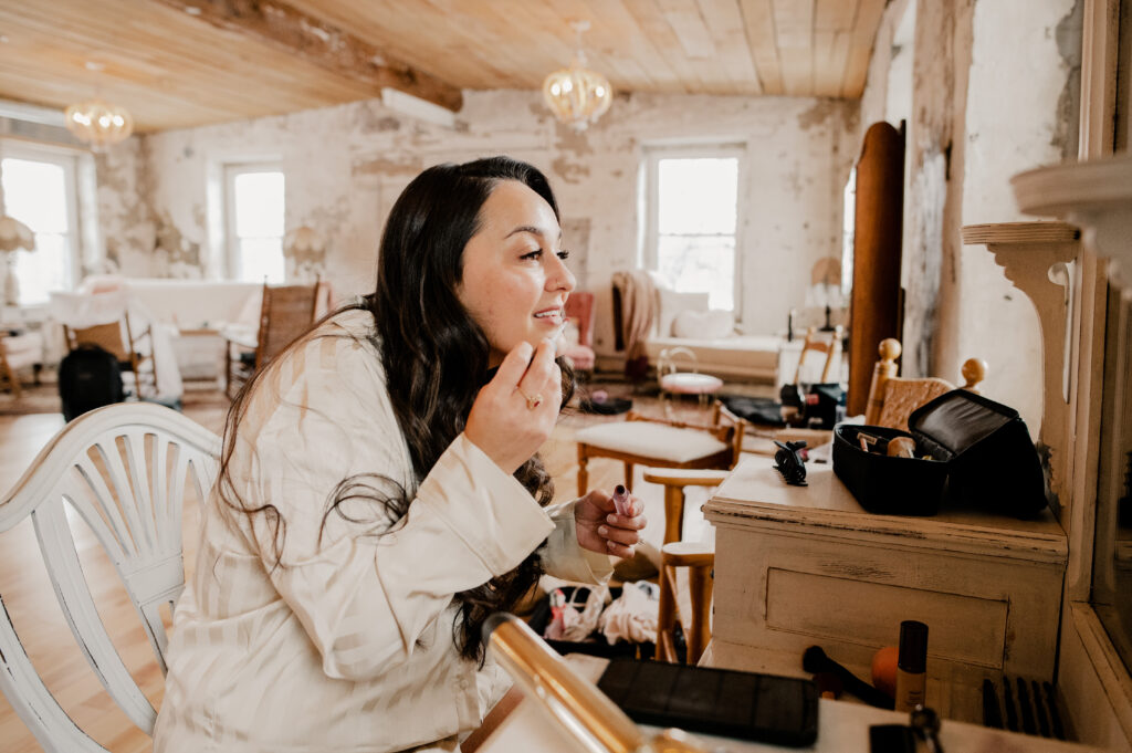 Bride fixing her lip gloss before her winter wedding at the Sinclair of Skaneateles.